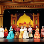 **Prompt:** A grand performance of Mozart's "The Marriage of Figaro" at Istana Budaya (Palace of Culture) in Kuala Lumpur, Malaysia. Capture the elegance of the opera house with Malay audience members in traditional batik clothing. Focus on the stage with vibrant costumes and dramatic lighting.